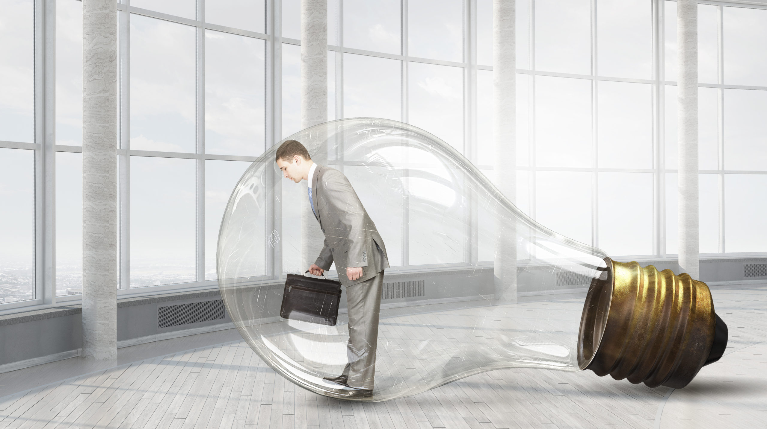 Frustrated businessman leaning with forehead on glass light bulb