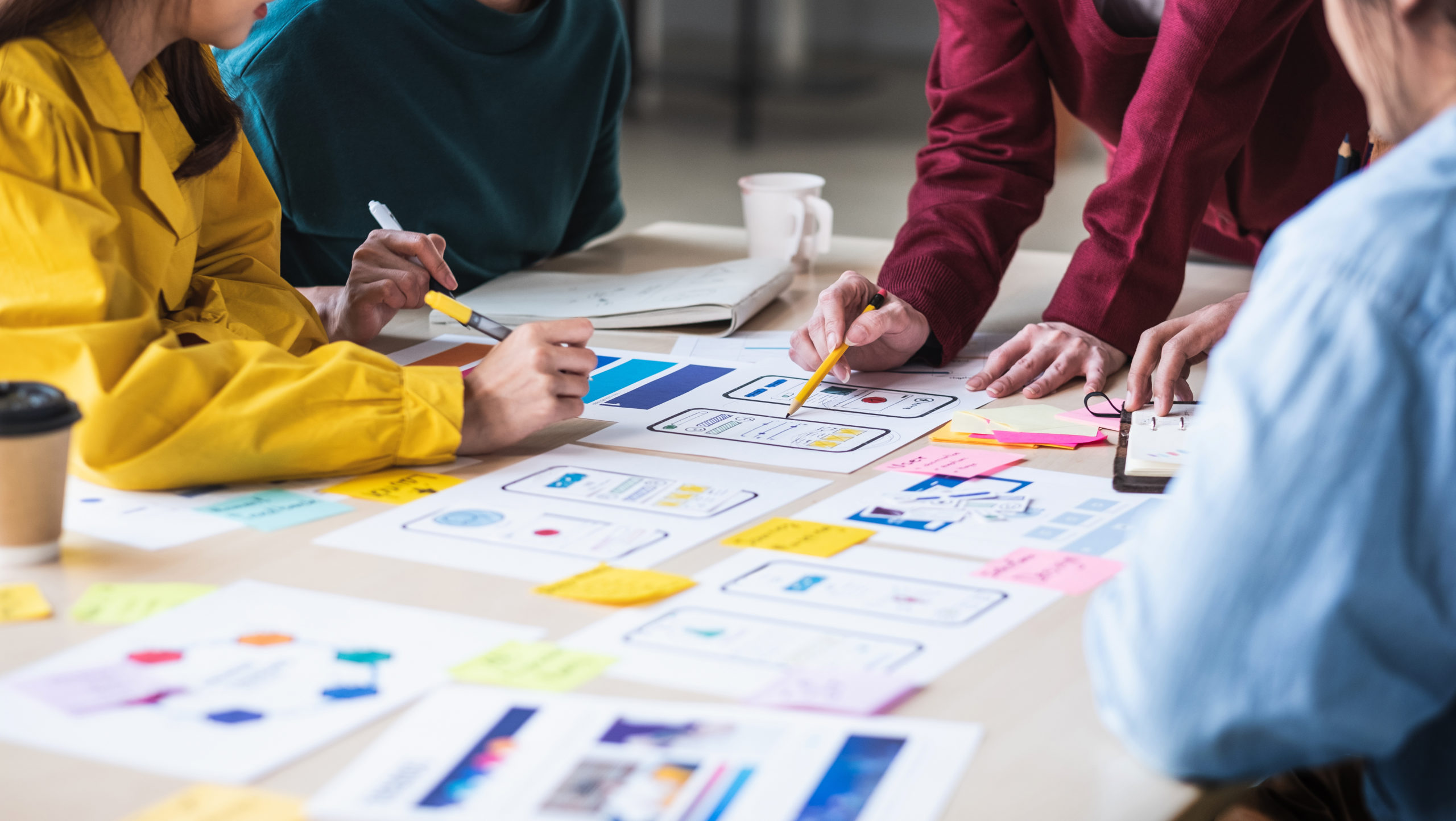 Close up ux developer and ui designer brainstorming about mobile app interface wireframe design on table with customer breif and color code at modern office.Creative digital development agency